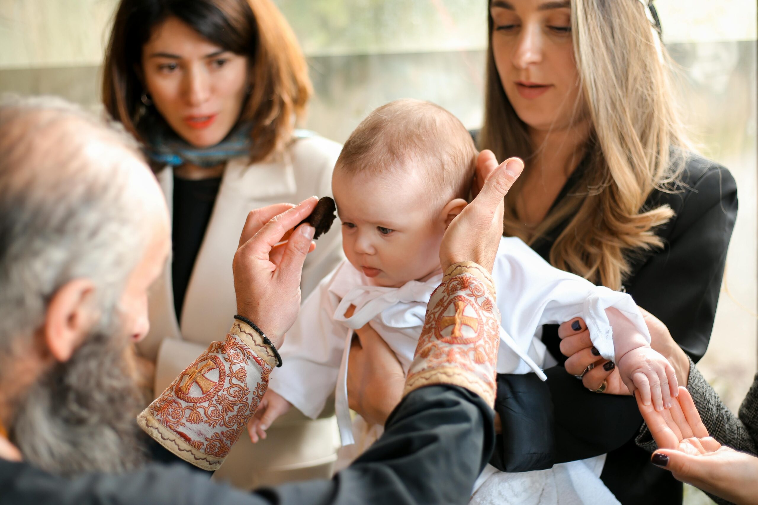 A touching moment during a baby's baptism, showcasing family and religious traditions.