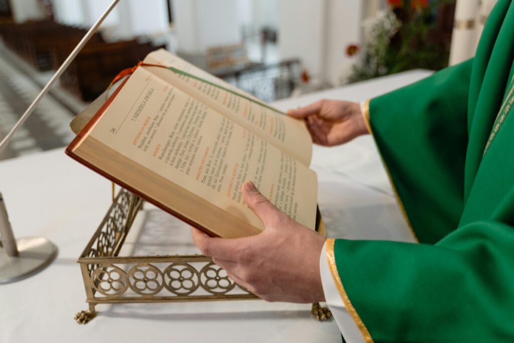 A priest holding an open religious book during a ceremony inside a church.